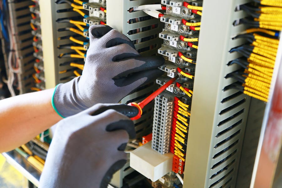 Electrician conducting finishing touches on electrical panel installation.