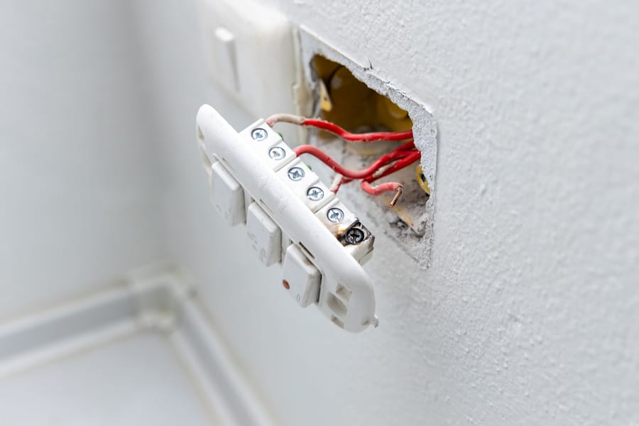 Exposed wires behind an outlet.