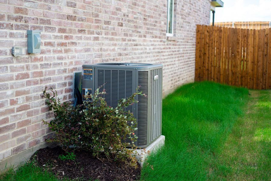 Outdoor HVAC unit and wall mounted electrical boxes installed alongside modern brick home